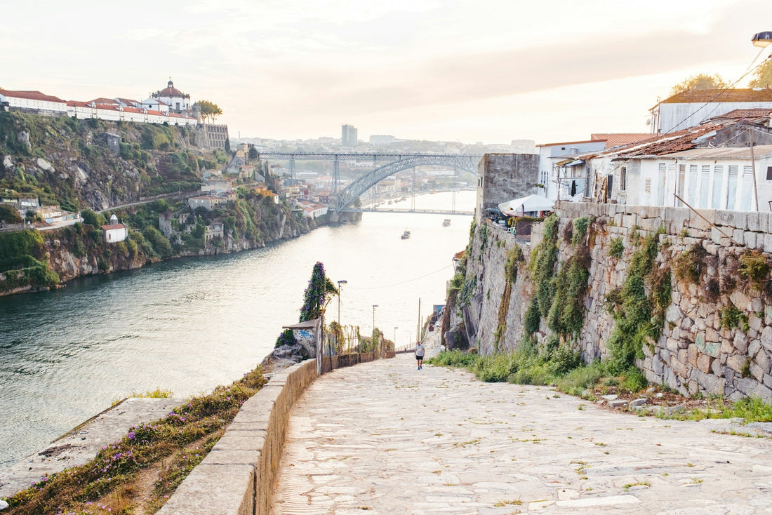 Blick über eine breite Steintreppe auf den Douro und die Brücke Dom Luís I in Porto im warmen Abendlicht.